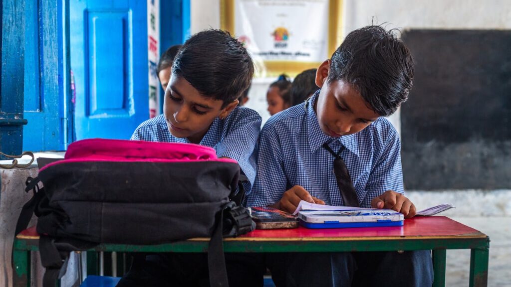 pexels-photo-18012463 Two Indian school boys in uniforms studying in a vibrant classroom setting.