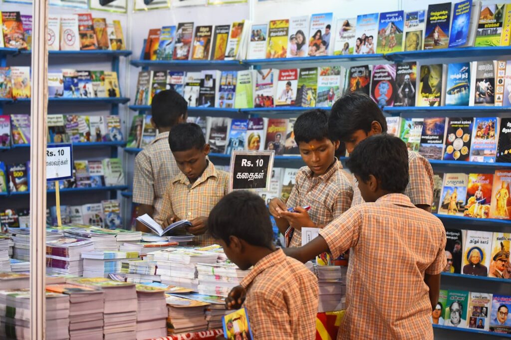 pexels-photo-28963924 Children engaged in browsing books at a stall in Madurai, highlighting interest in reading and education.
